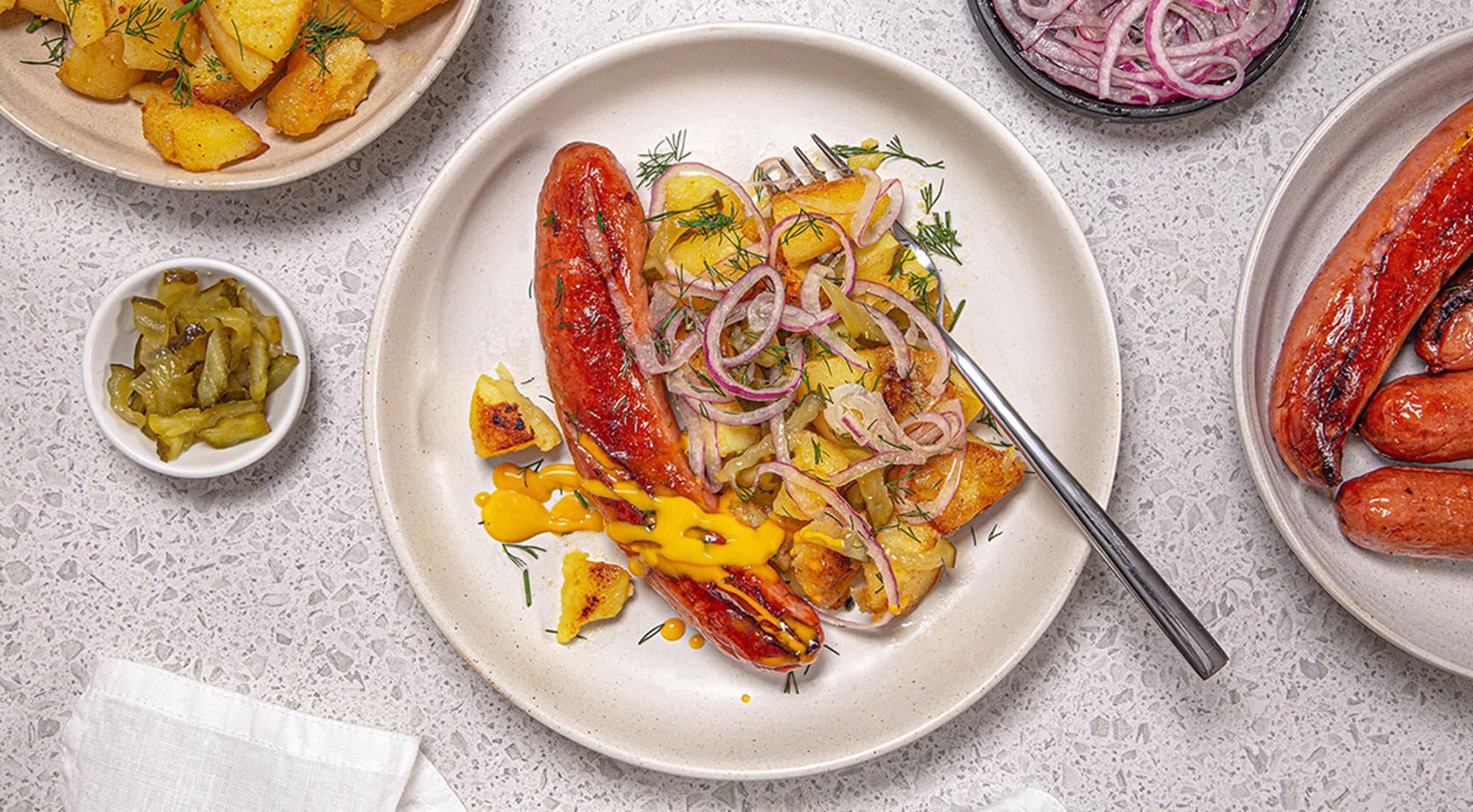 Stekte pølser med knuste mandelpoteter og syltet rødløk